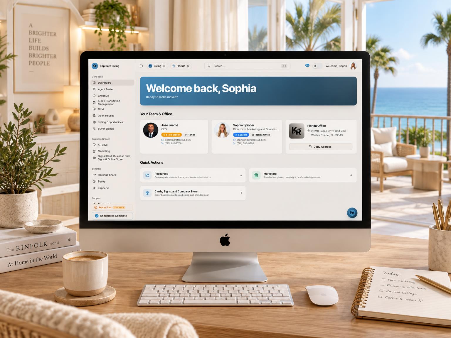 Virtual office dashboard on a desktop computer in a bright home office overlooking an ocean balcony